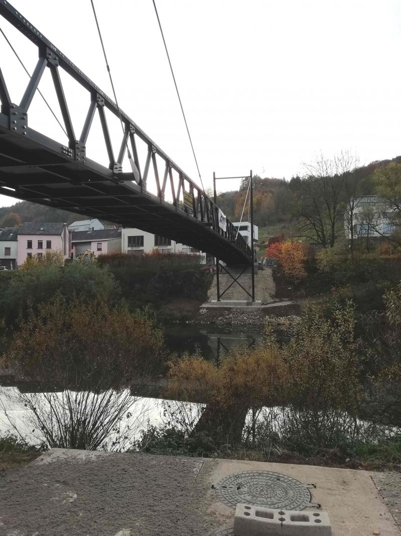 Vorab wurde der erste Pylon gesetzt. Die in vier Teilen angelieferte Brücke selbst wurde daraufhin eingeschwenkt und gleichzeitig der zweite Pylon befestigt. Für die Anlieferung, den Zusammenbau der vorgefertigten Abschnitte am Baugrund sowie das finale Einschwenken waren insgesamt lediglich sieben Tage notwendig. Quelle: PML